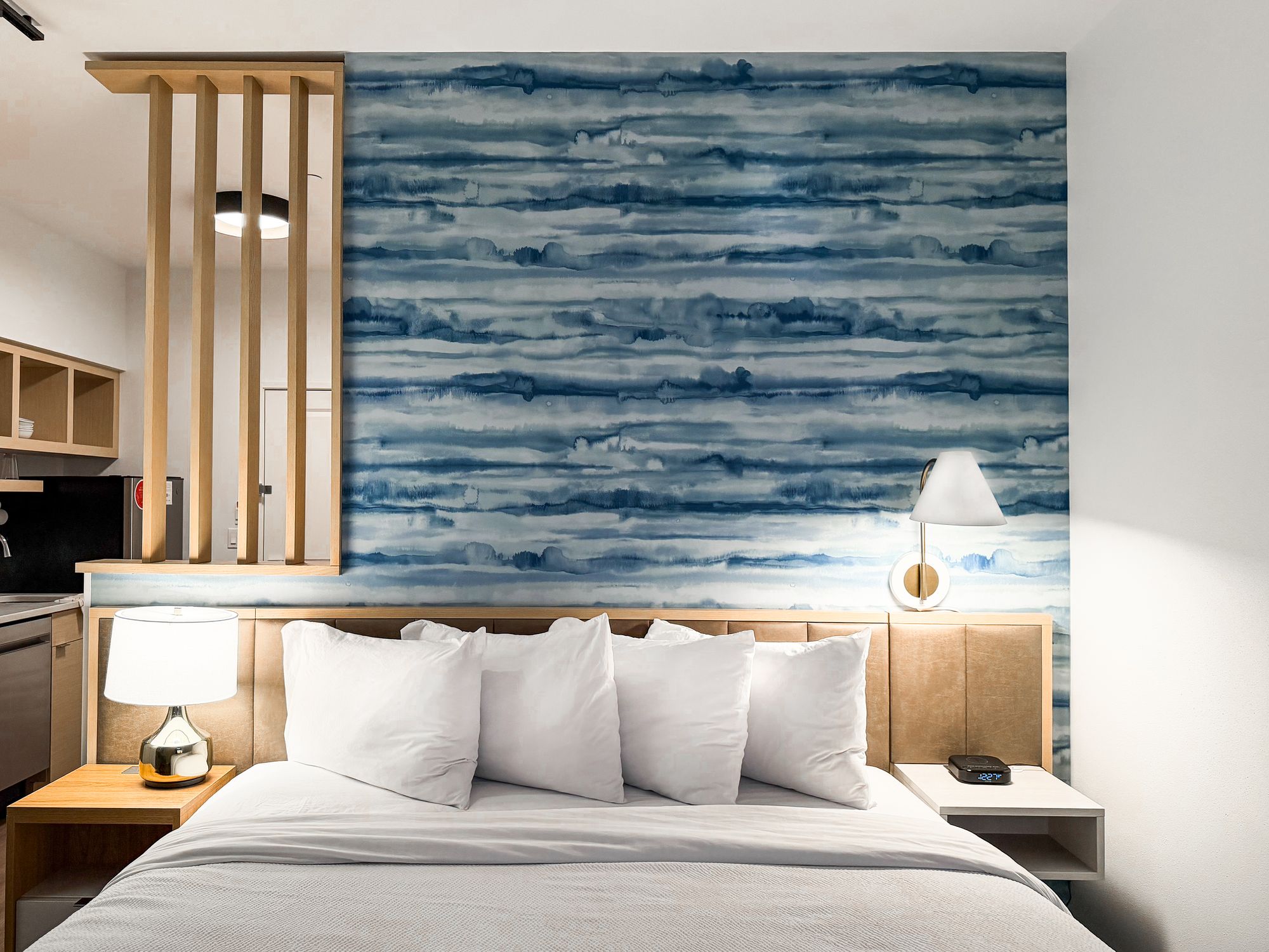Marriott suite bedroom with white bedding against a blue watercolor accent wall