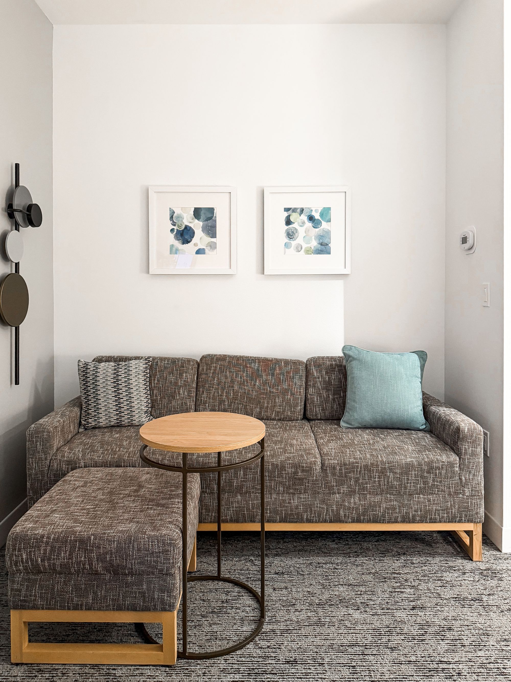 Marriott suite living area with a sectional sofa, ottoman, and abstract blue art
