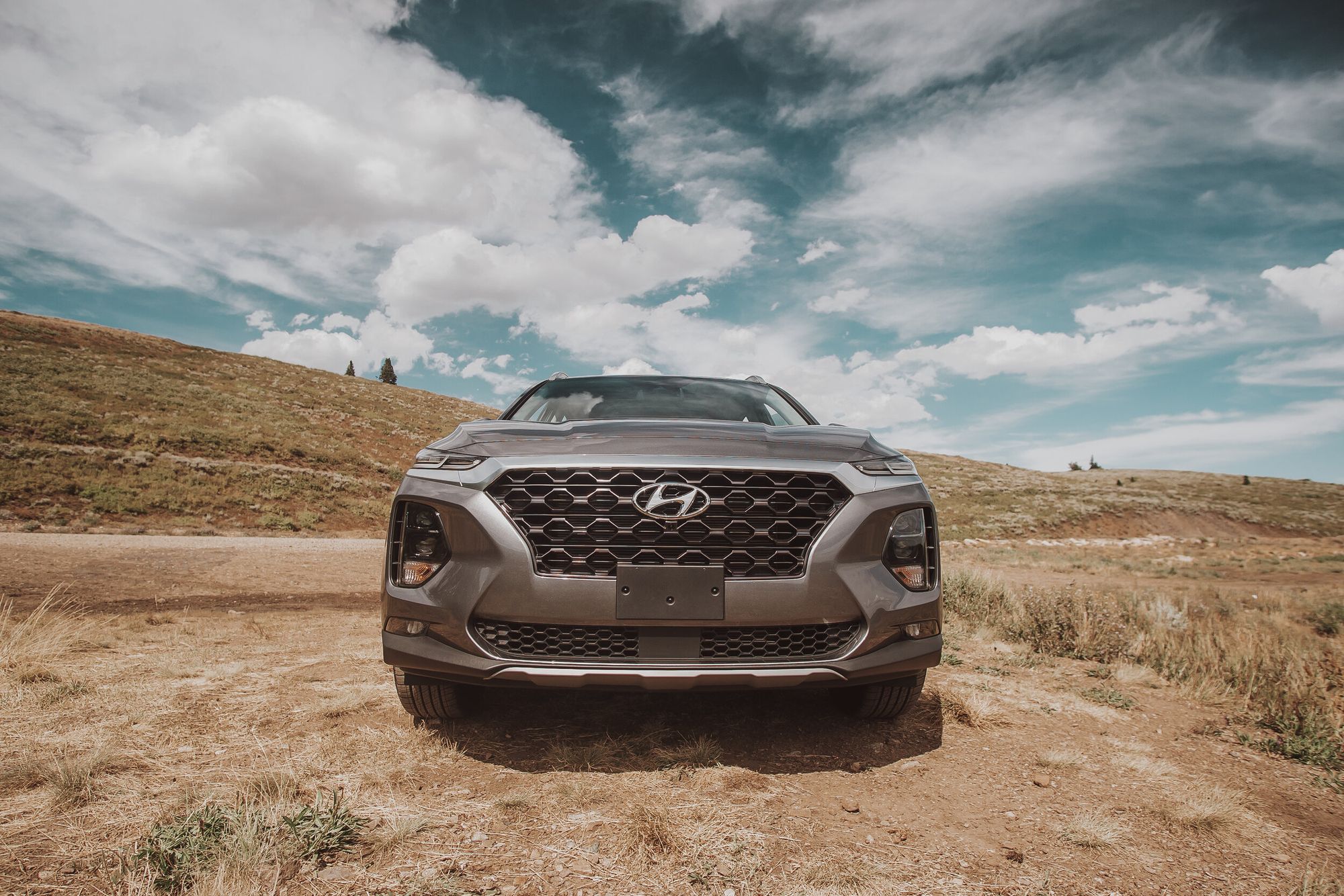 Front view of a Hyundai Santa Fe on a mountain trail beneath a dramatic sky